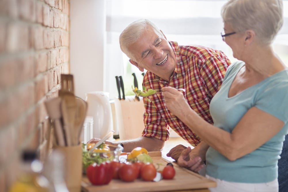 Senior couple preparing vegetables in kitchen for home care.