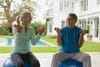 Two people sitting on exercise balls in front of a house.