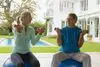 Two people sitting on exercise balls in front of a house.