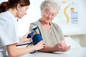 A nurse is checking the blood pressure of an elderly woman.