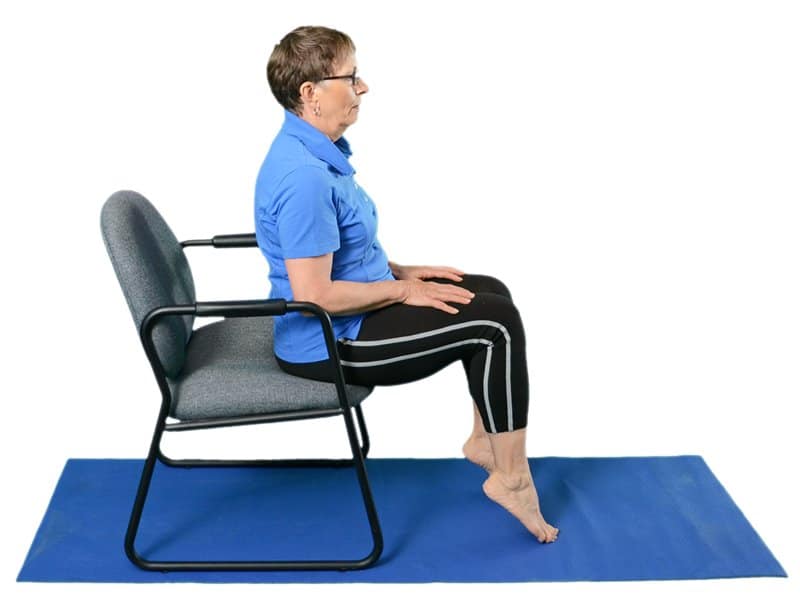 A elderly woman performing safe exercises on a yoga mat.