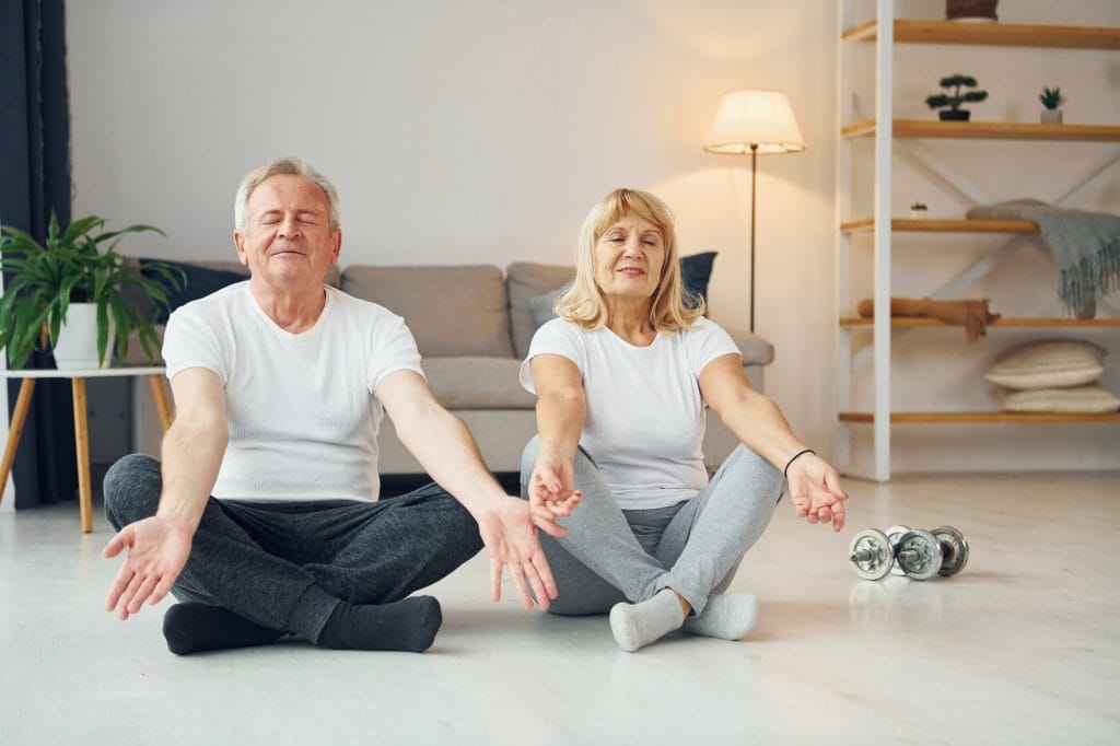 Senior couple doing yoga in the living room.