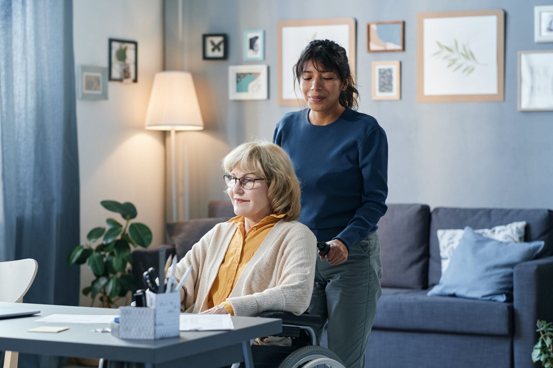 A woman in a wheelchair is being helped by a caregiver.
