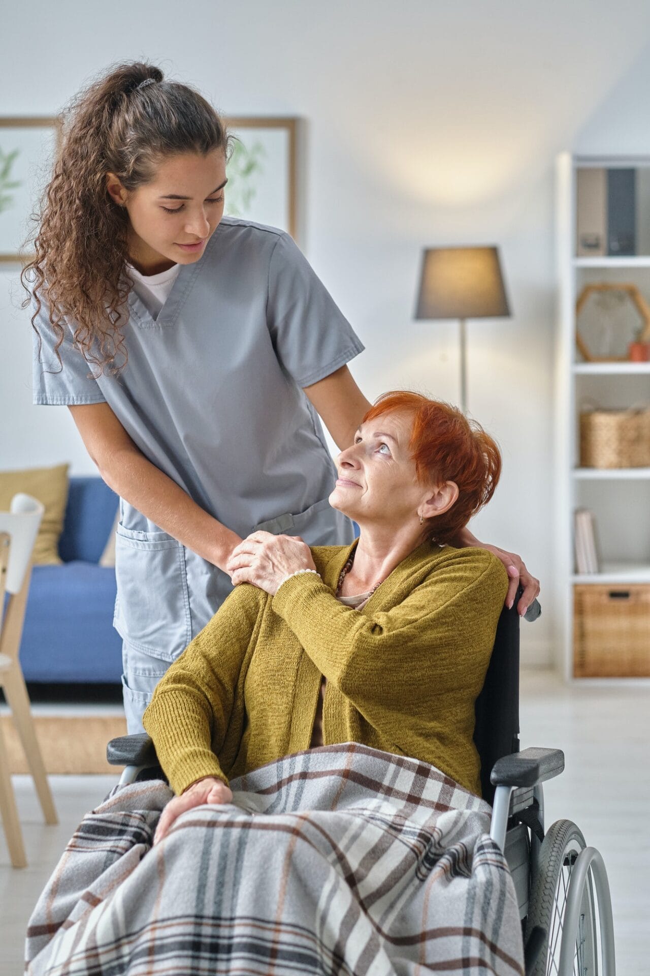 A nurse is helping an elderly woman in a wheelchair.