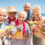 A group of elderly people enjoying drinks on the beach.