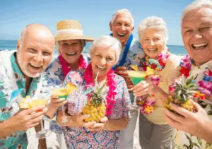 A group of elderly people enjoying drinks on the beach.