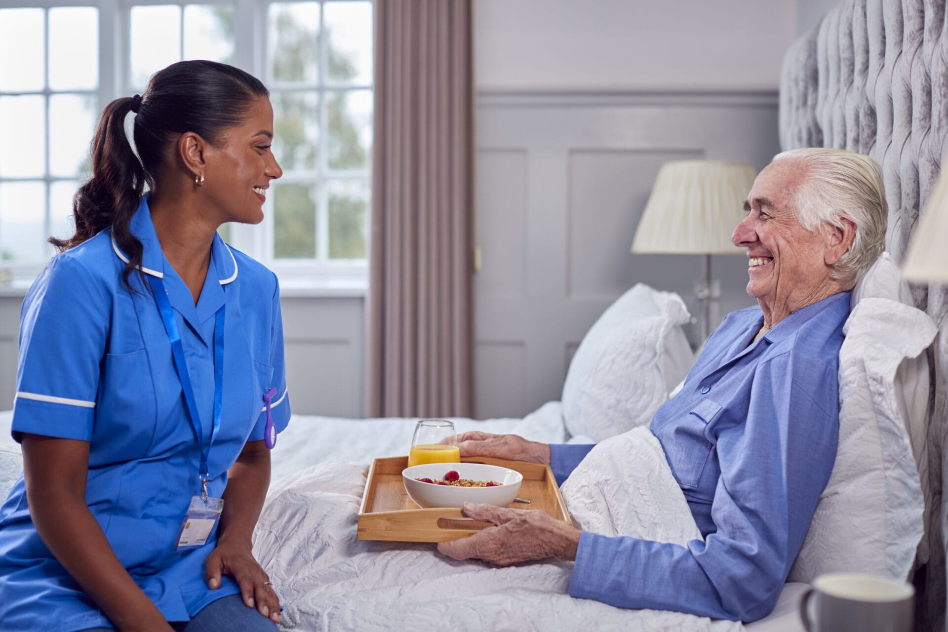 A nurse is talking to an elderly man in bed.