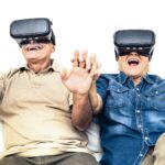 Senior mature couple having fun together with virtual reality headset sitting on sofa