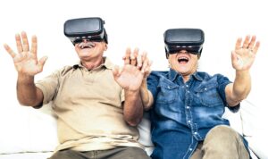 Senior mature couple having fun together with virtual reality headset sitting on sofa