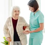 Caregiver helping elderly woman to walk