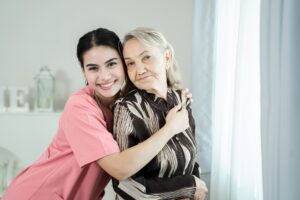 Professional helpful caregiver comforting senior woman at nursing home.