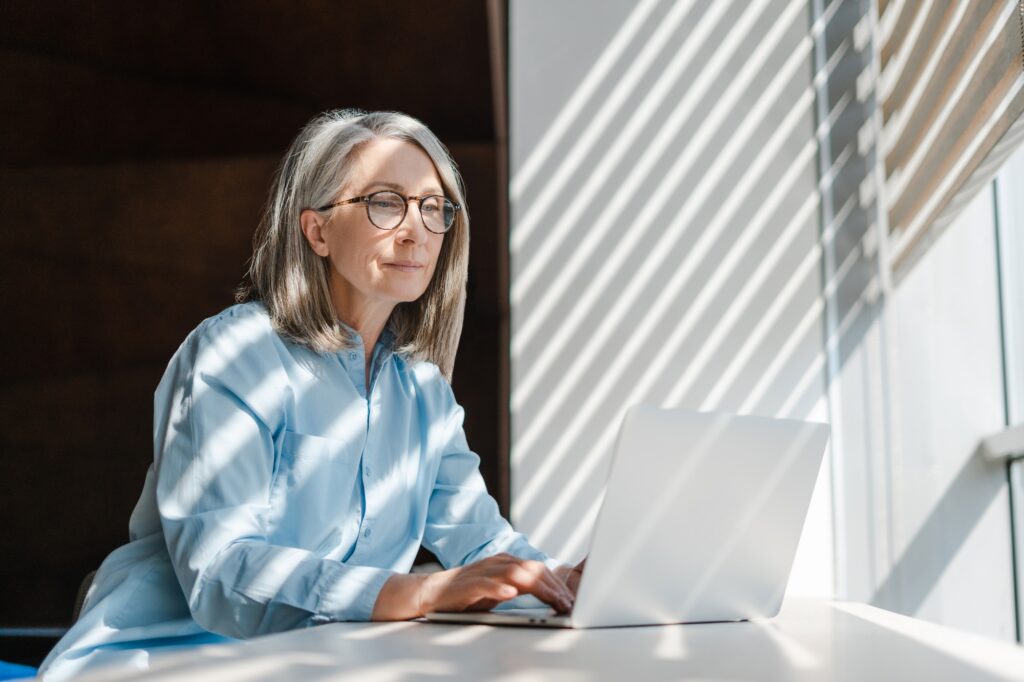Senior businesswoman using laptop computer working online sitting in modern office