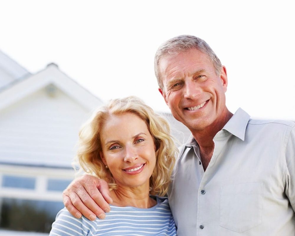 An older couple posing in front of why they chose their new home.