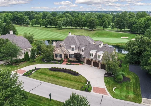 An aerial view of a home with a golf course in the background.