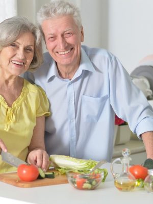 Senior couple preparing vegetables in home kitchen.