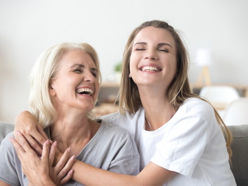 Two women providing non medical home care support embrace on a couch.