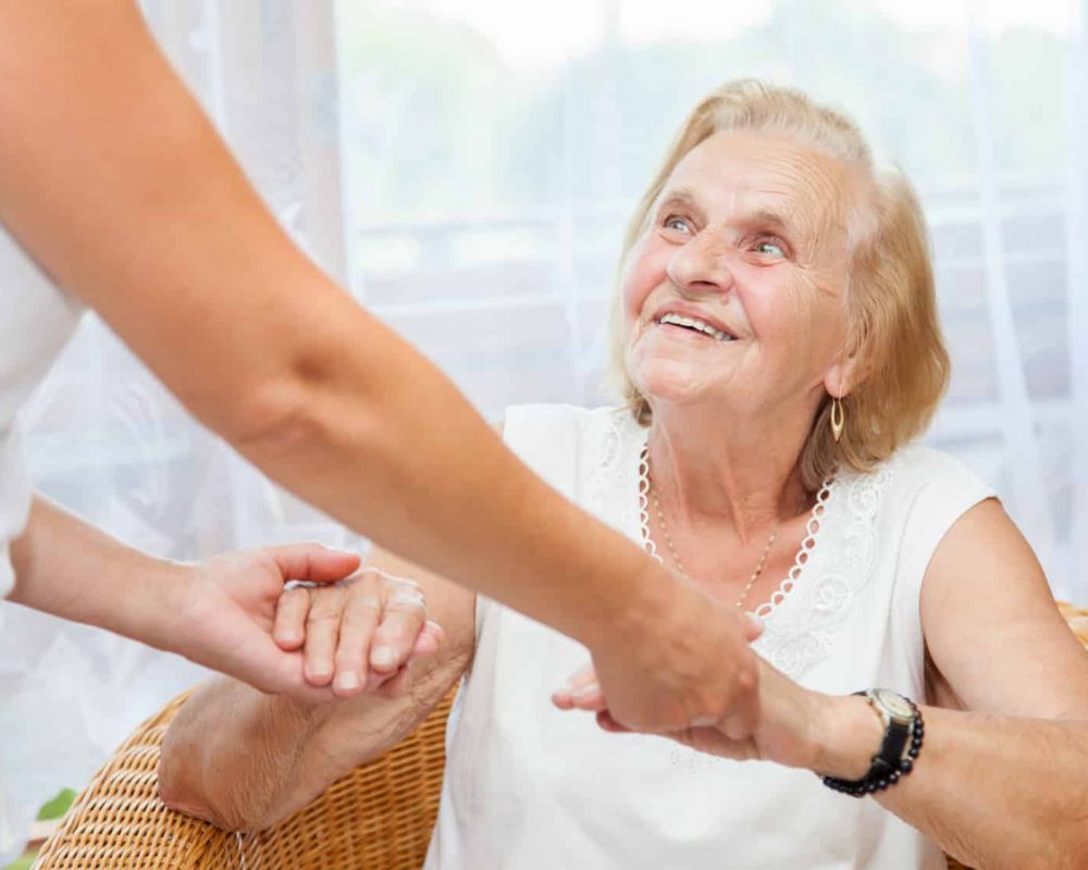A woman is engaging in a handshake with an elderly woman, illustrating the connection forged between generations.