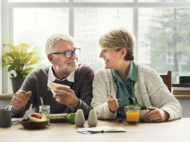 An elder couple enjoying home care while eating breakfast together.