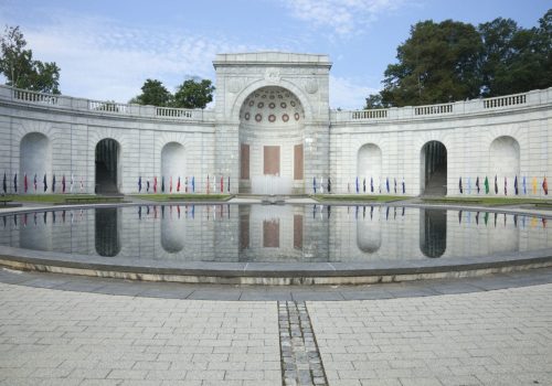 A fountain in the middle of a courtyard with many flags.